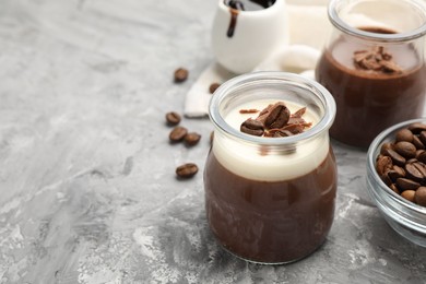 Photo of Delicious panna cotta with chocolate chunks and coffee beans on grey textured table, closeup. Space for text
