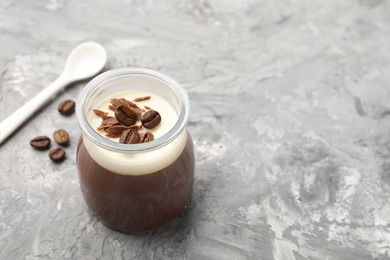 Photo of Delicious panna cotta with chocolate chunks and coffee beans on grey textured table. Space for text