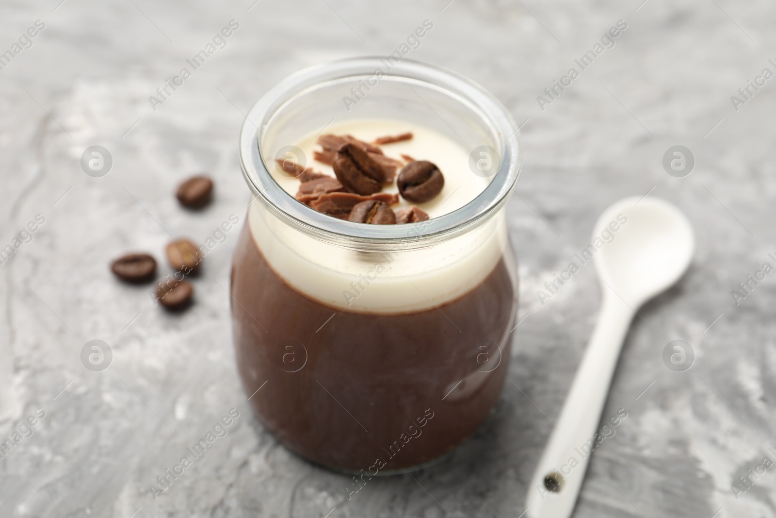 Delicious panna cotta with chocolate chunks and coffee beans on grey textured table, closeup Photo of Delicious panna cotta with chocolate chunks and coffee beans on grey textured table, closeup