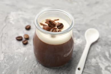 Photo of Delicious panna cotta with chocolate chunks and coffee beans on grey textured table, closeup