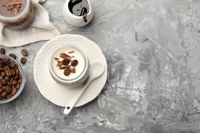 Photo of Delicious panna cotta with chocolate chunks and coffee beans served on grey textured table, flat lay. Space for text