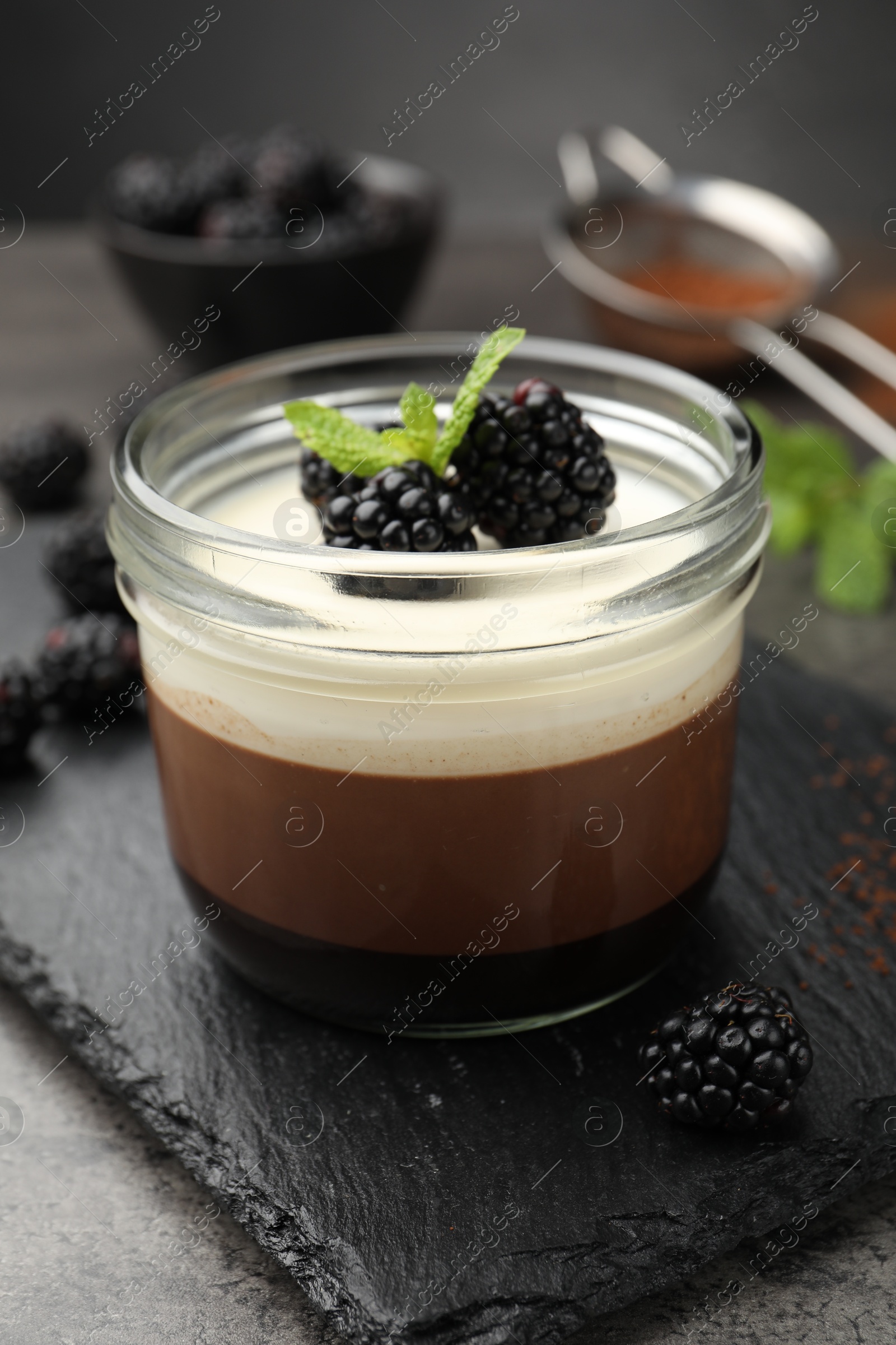 Tasty panna cotta with blackberries and mint in jar at grey table, closeup Photo of Tasty panna cotta with blackberries and mint in jar at grey table, closeup