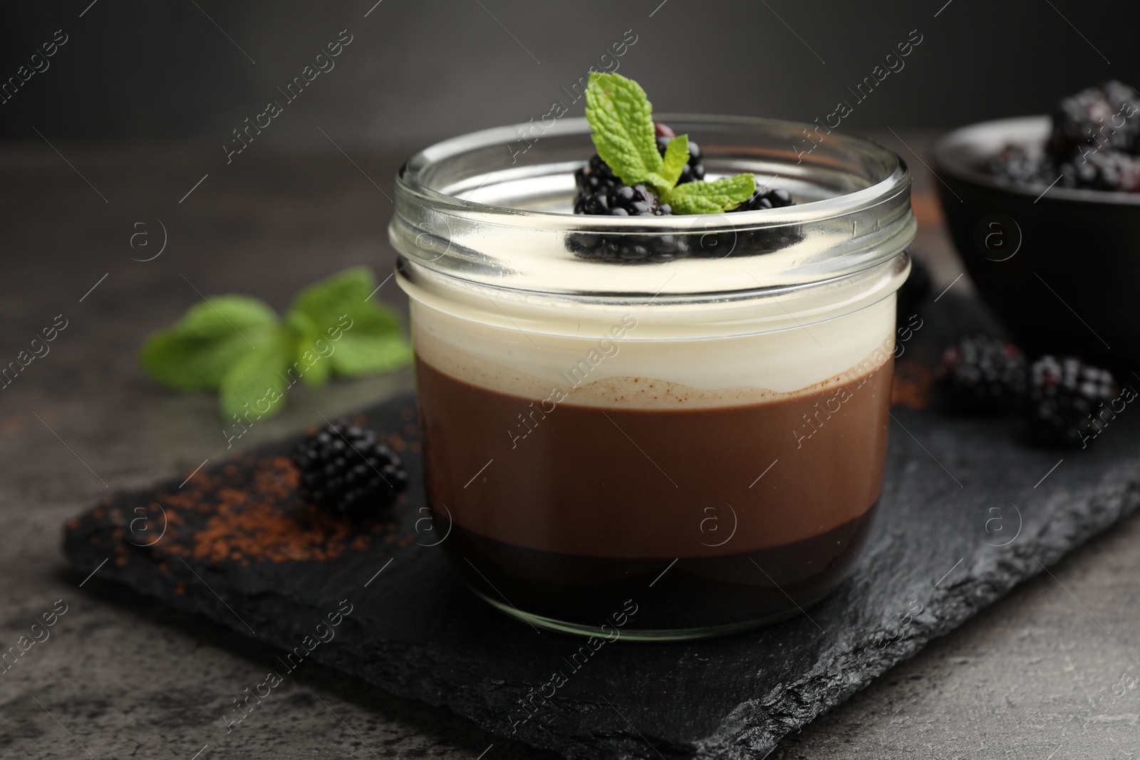 Tasty panna cotta with blackberries and mint in jar at grey table, closeup Photo of Tasty panna cotta with blackberries and mint in jar at grey table, closeup