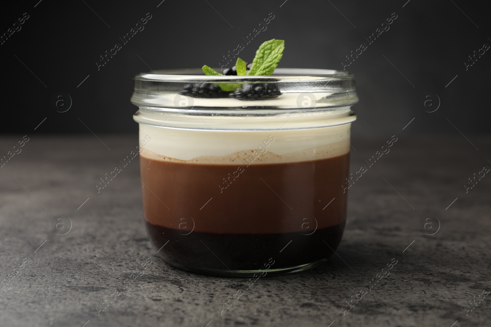 Tasty panna cotta with blackberries and mint in jar at grey table, closeup Photo of Tasty panna cotta with blackberries and mint in jar at grey table, closeup