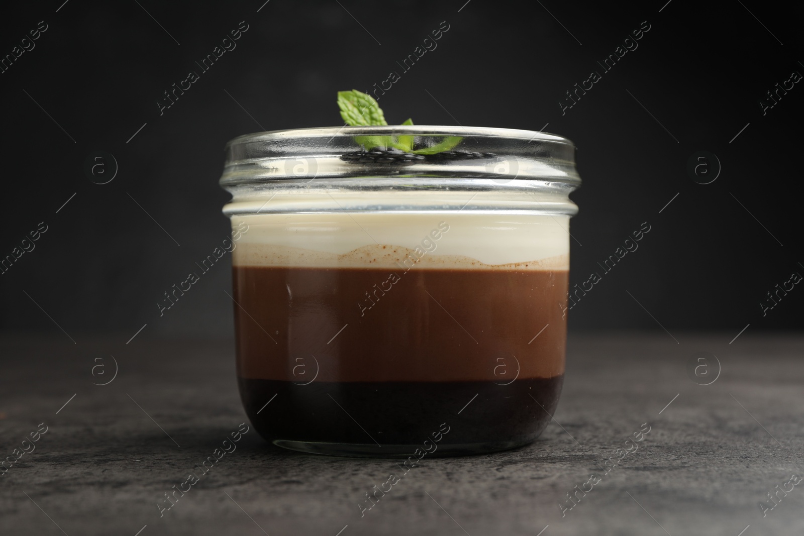 Tasty panna cotta with blackberries and mint in jar at grey table, closeup Photo of Tasty panna cotta with blackberries and mint in jar at grey table, closeup