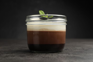 Photo of Tasty panna cotta with blackberries and mint in jar at grey table, closeup