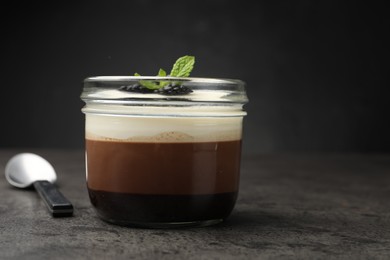 Photo of Tasty panna cotta with blackberries and mint in jar at grey table, closeup
