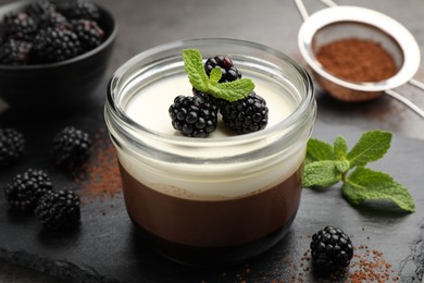 Photo of Tasty panna cotta with blackberries, mint and cocoa powder on grey table, closeup