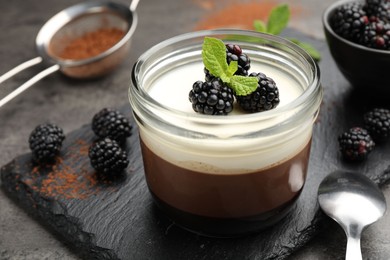 Photo of Tasty panna cotta with blackberries, mint and cocoa powder on grey table, closeup