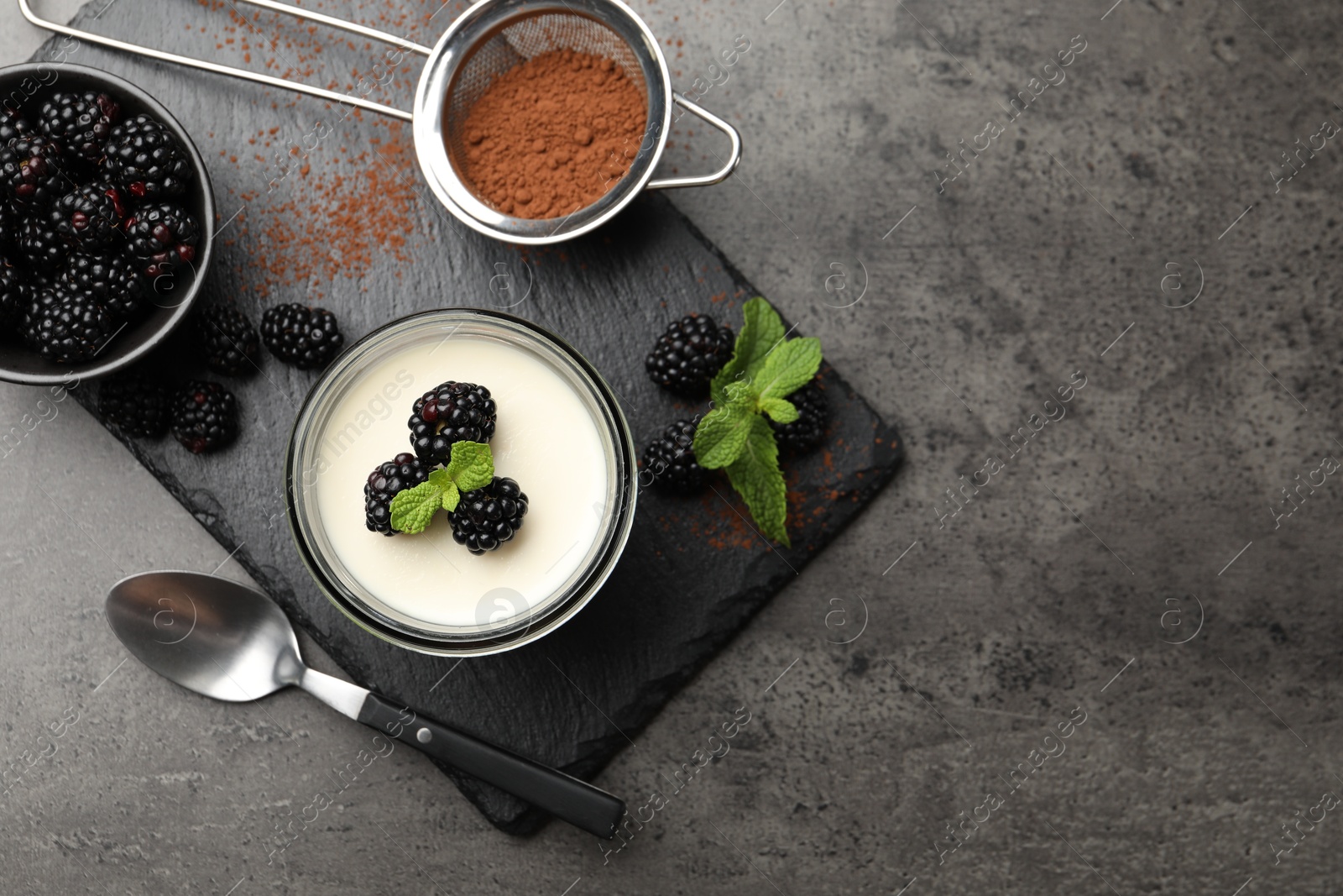Tasty panna cotta with blackberries, mint and cocoa powder on grey table, flat lay. Space for text Photo of Tasty panna cotta with blackberries, mint and cocoa powder on grey table, flat lay. Space for text