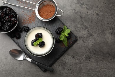 Photo of Tasty panna cotta with blackberries, mint and cocoa powder on grey table, flat lay. Space for text