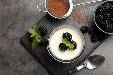 Photo of Tasty panna cotta with blackberries, mint and cocoa powder on grey table, flat lay