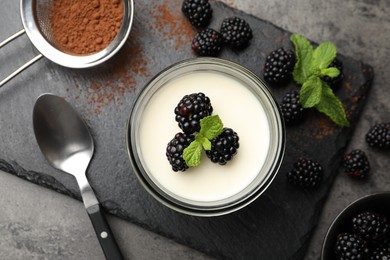 Photo of Tasty panna cotta with blackberries, mint and cocoa powder on grey table, flat lay
