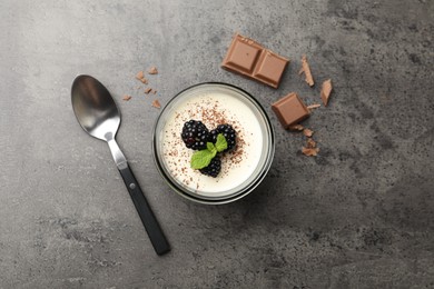 Photo of Tasty panna cotta with blackberries, mint and chocolate pieces on grey table, flat lay