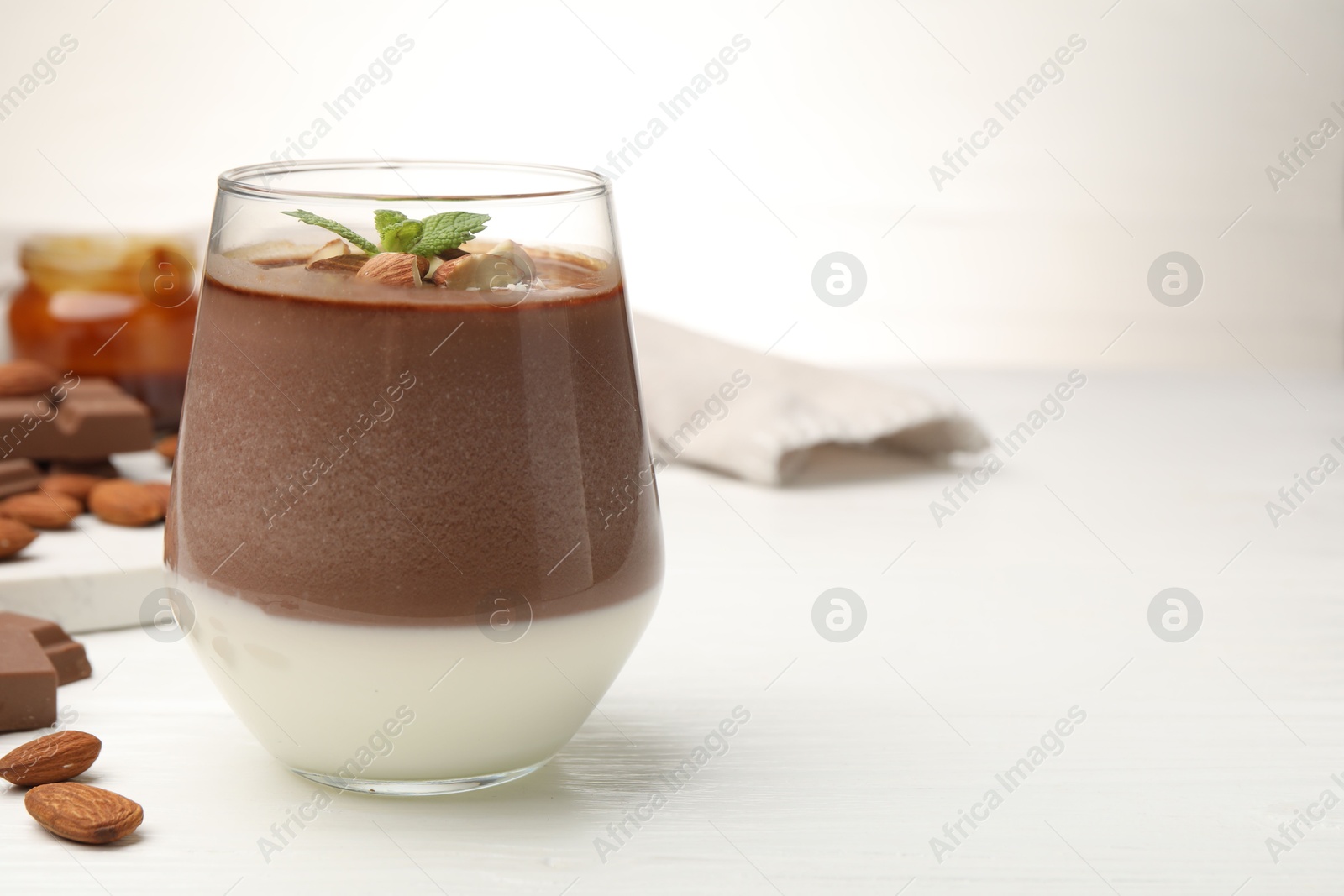 Delicious chocolate panna cotta with almonds and mint on white wooden table, closeup. Space for text Photo of Delicious chocolate panna cotta with almonds and mint on white wooden table, closeup. Space for text
