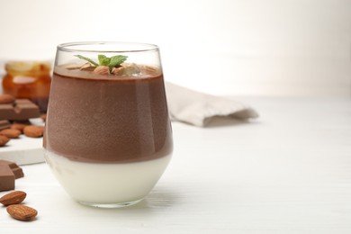 Photo of Delicious chocolate panna cotta with almonds and mint on white wooden table, closeup. Space for text