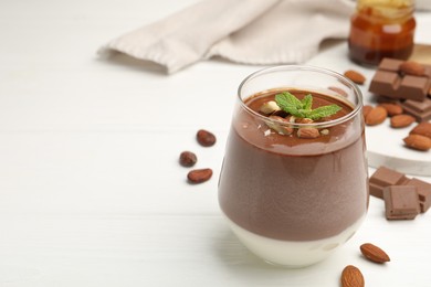 Photo of Delicious chocolate panna cotta with almonds and mint on white wooden table, closeup. Space for text