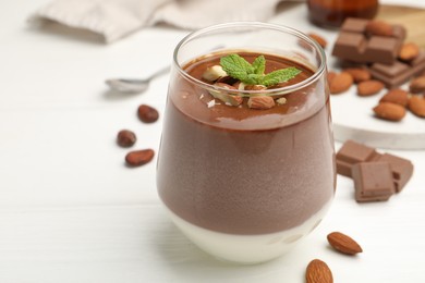 Photo of Delicious chocolate panna cotta with almonds and mint on white wooden table, closeup