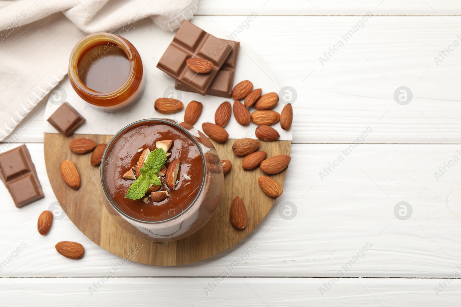 Delicious chocolate panna cotta with almonds, mint and caramel sauce on white wooden table, flat lay. Space for text Photo of Delicious chocolate panna cotta with almonds, mint and caramel sauce on white wooden table, flat lay. Space for text