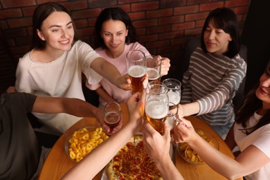 Photo of Group of happy friends clinking glasses of beer at table indoors, above view