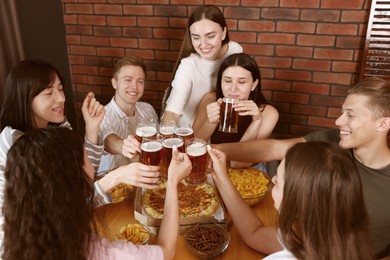 Photo of Group of happy friends clinking glasses of beer indoors