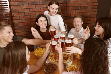 Photo of Group of happy friends clinking glasses of beer indoors