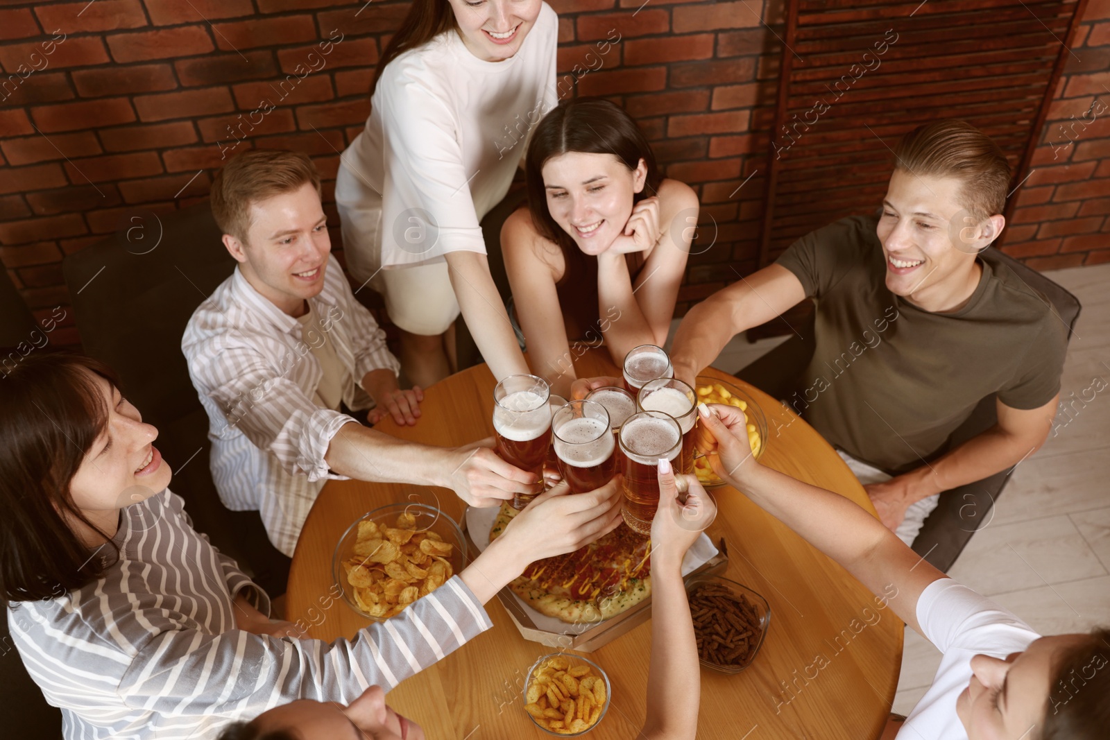 Photo of Group of happy friends clinking glasses of beer indoors