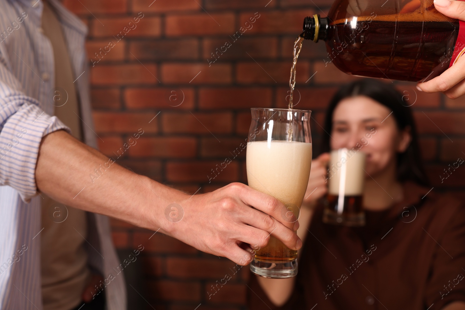 Photo of Young woman pouring beer into glass indoors, selective focus