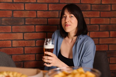 Photo of Young woman with glass of beer at table with food in bar