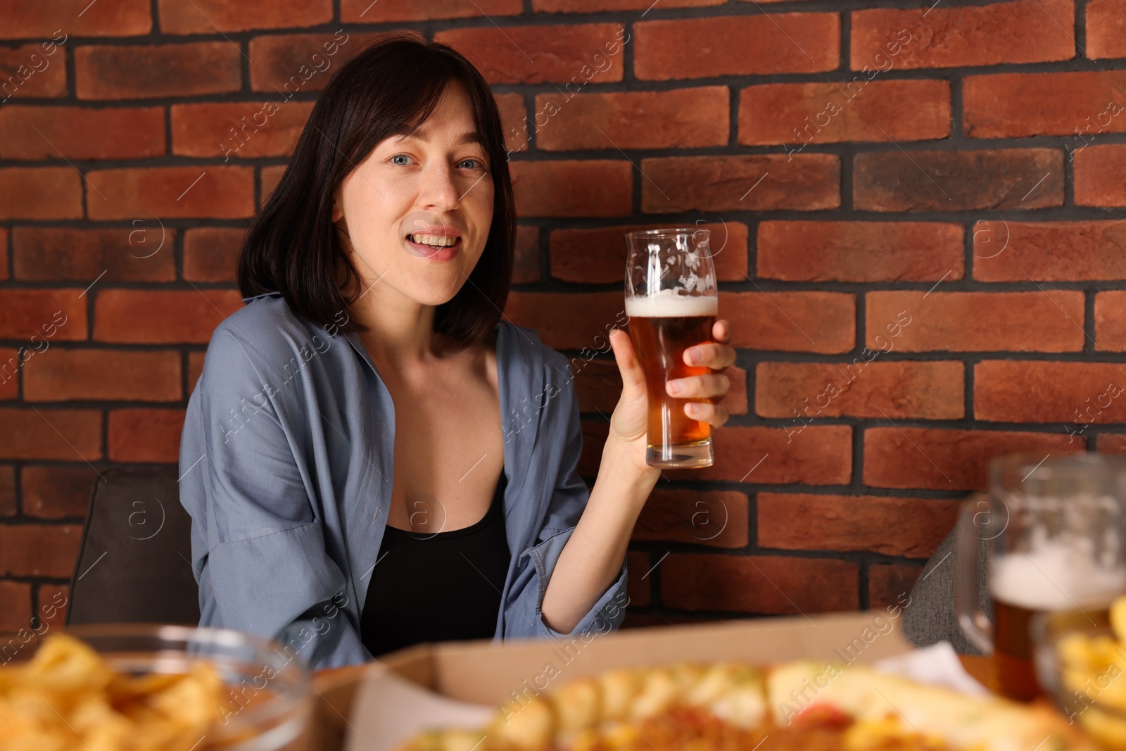 Photo of Young woman with glass of beer at table with food in bar