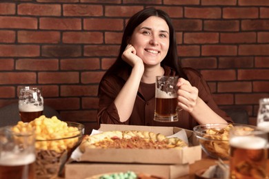 Photo of Young woman with glass of beer at table with food in bar