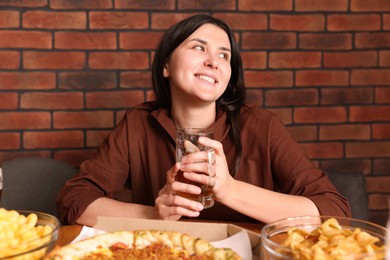 Photo of Young woman with glass of beer at table with food in bar