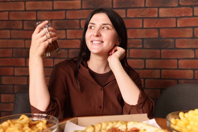 Photo of Young woman with glass of beer at table with food in bar