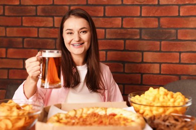 Photo of Young woman with glass of beer at table with food in bar