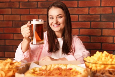 Photo of Young woman with glass of beer at table with food in bar