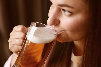 Photo of Young woman drinking beer from glass indoors, closeup