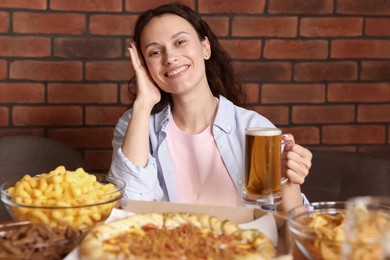 Photo of Young woman with glass of beer at table with food in bar