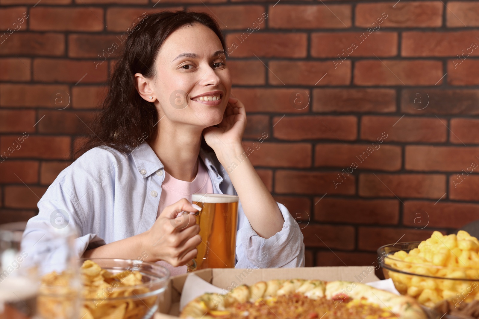 Photo of Young woman with glass of beer at table with food in bar