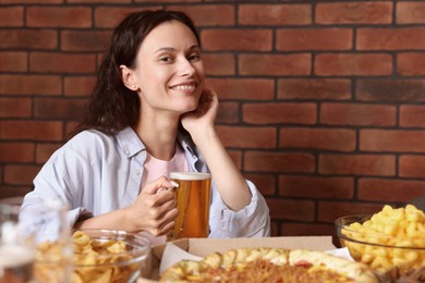 Photo of Young woman with glass of beer at table with food in bar