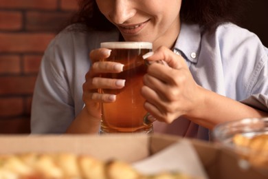 Photo of Young woman drinking beer at table with food in bar, closeup