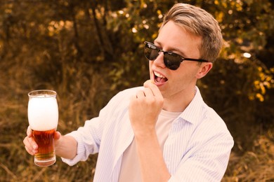 Photo of Handsome young man with glass of beer outdoors