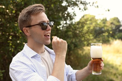 Photo of Handsome young man with glass of beer outdoors