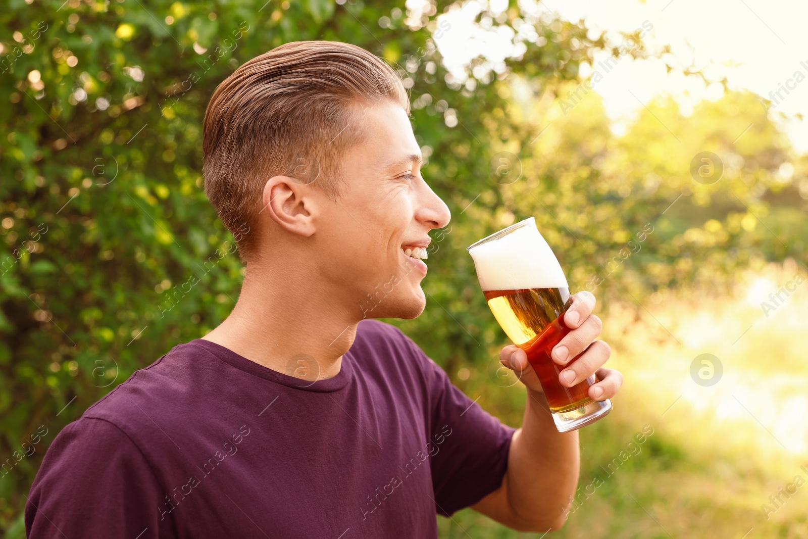 Photo of Young man drinking beer from glass outdoors