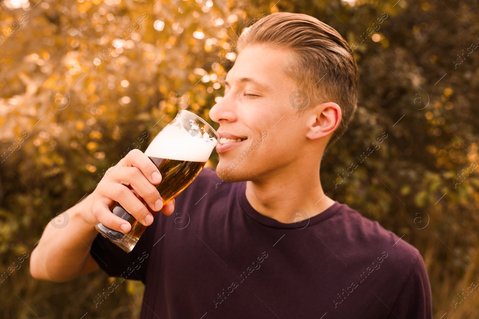 Photo of Young man drinking beer from glass outdoors
