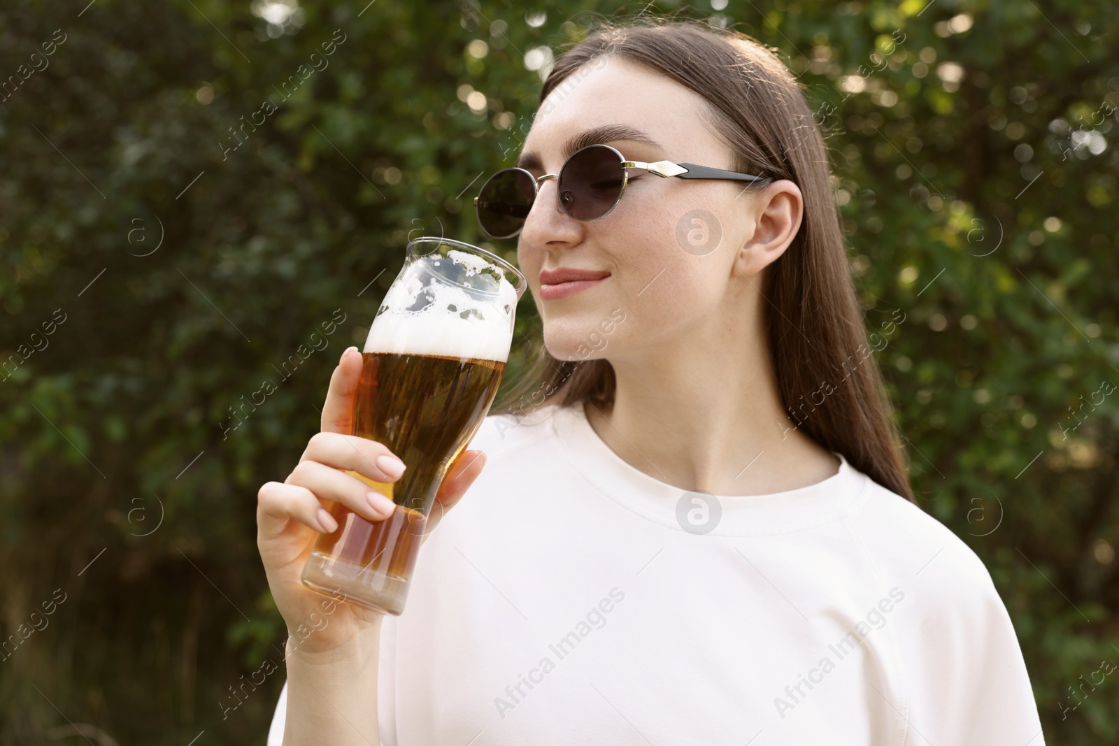 Photo of Young woman drinking beer from glass outdoors