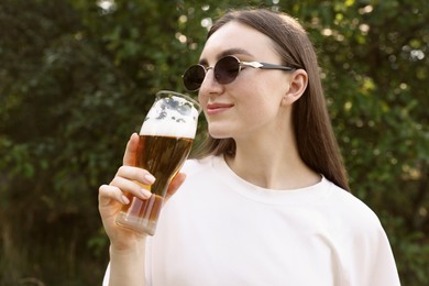 Photo of Young woman drinking beer from glass outdoors
