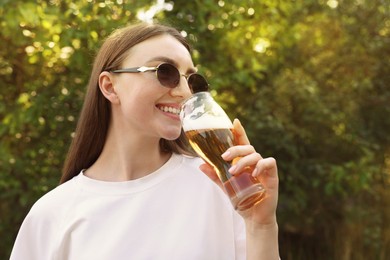 Photo of Young woman drinking beer from glass outdoors