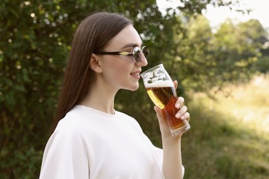 Photo of Young woman drinking beer from glass outdoors