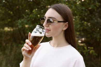Photo of Young woman drinking beer from glass outdoors