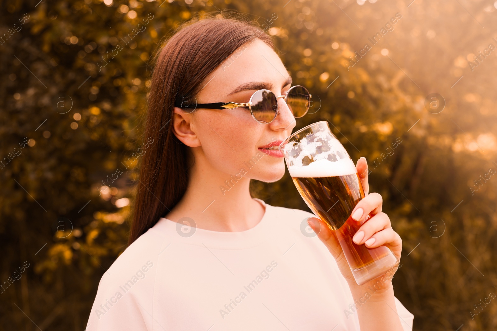 Photo of Young woman drinking beer from glass outdoors